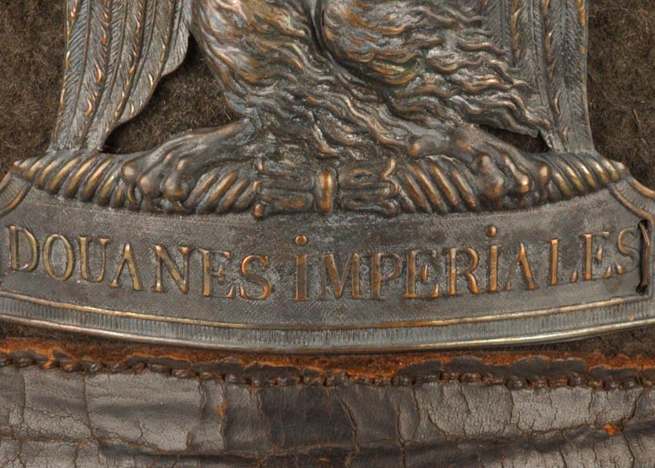 Detail of a French Napoleonic era uniform, showing a metal badge with the words 'Douanes Imperiales' visible